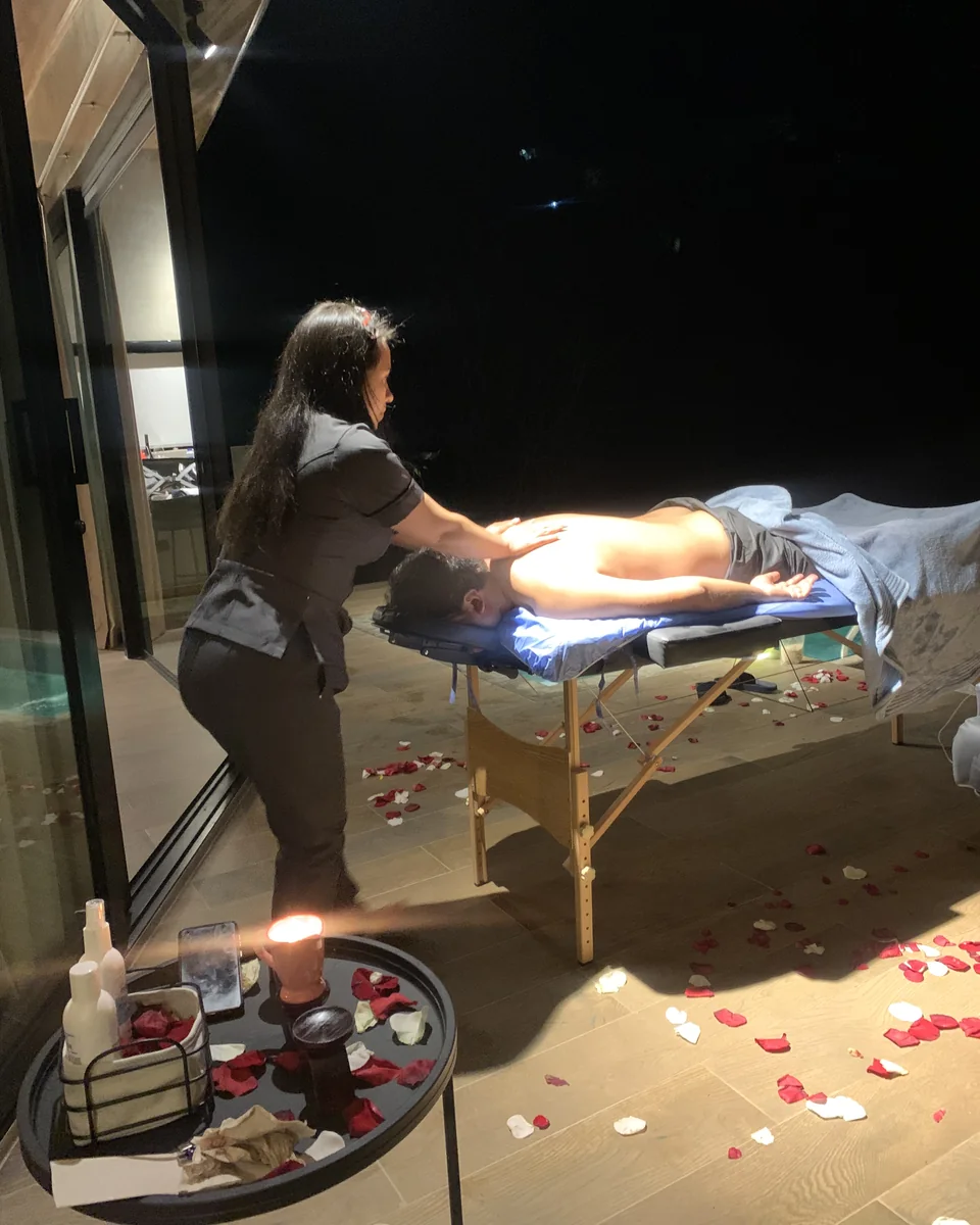 Masaje en la terraza de la villa, de noche, entre pétalos y la luz de una vela