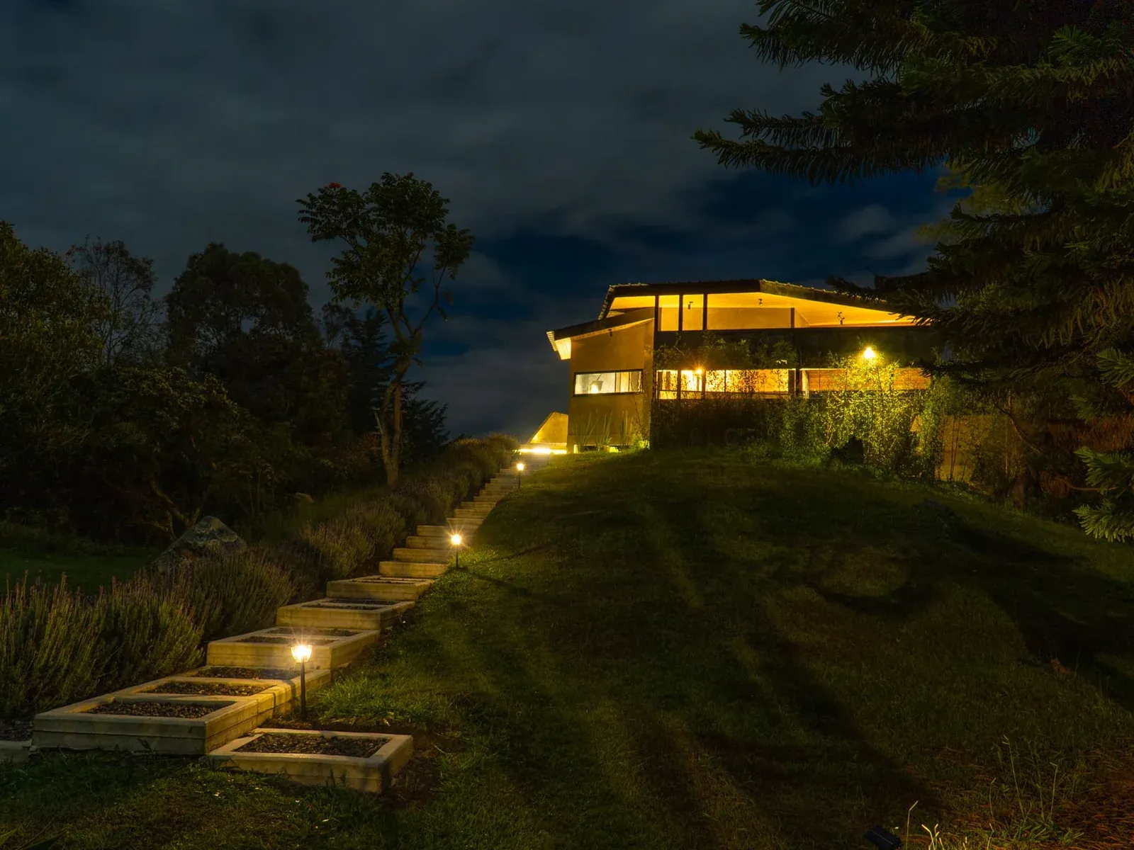 Sendero iluminado de llegada a una villa de AlmazewÁ, de noche